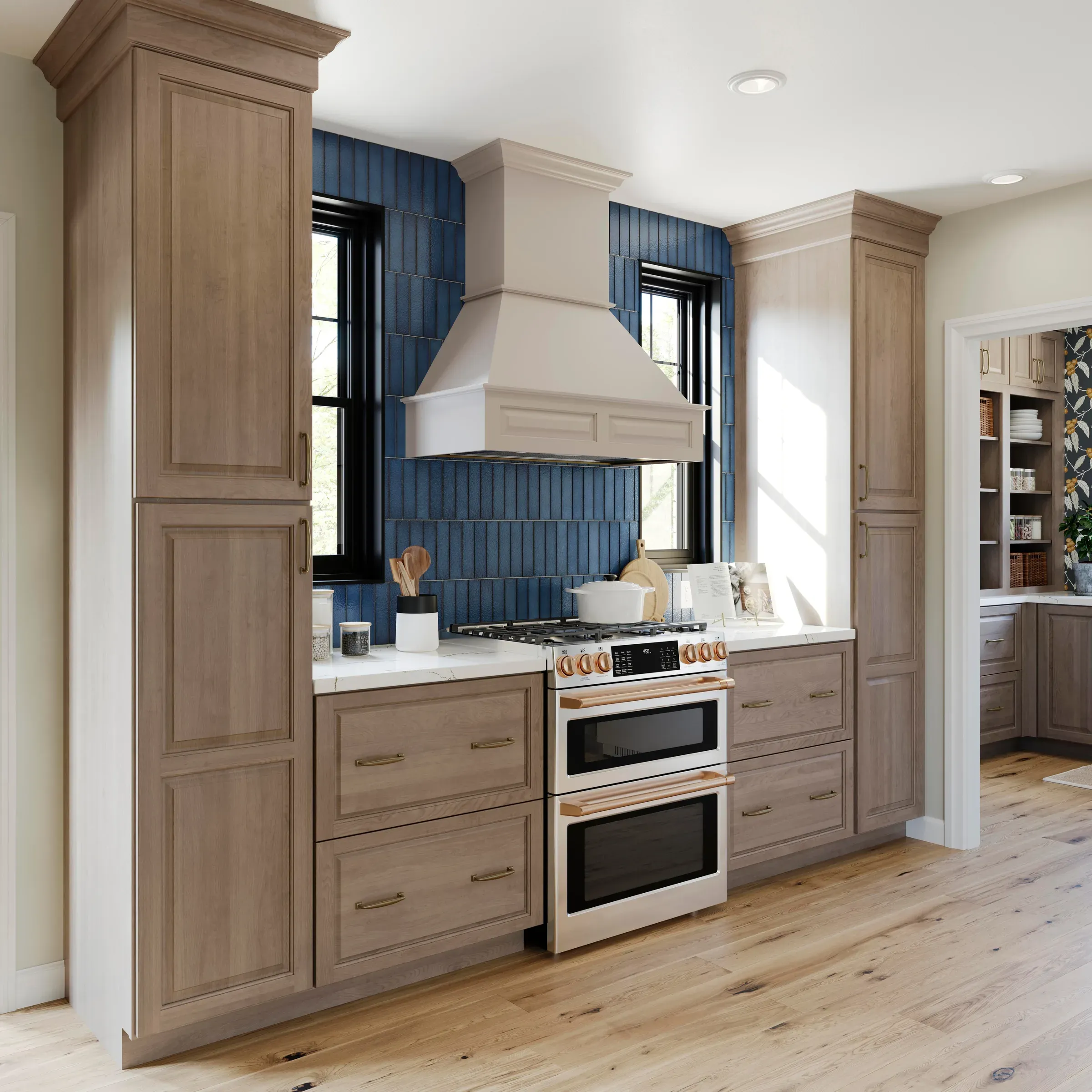 Range wall detail: painted hood surround, vertical blue tile, double wall ovens, and a tall pantry cabinet.