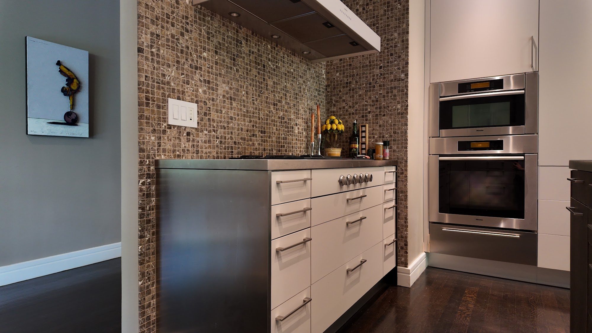 Stone mosaic backsplash and integrated range hood running into the upper cabinet line.