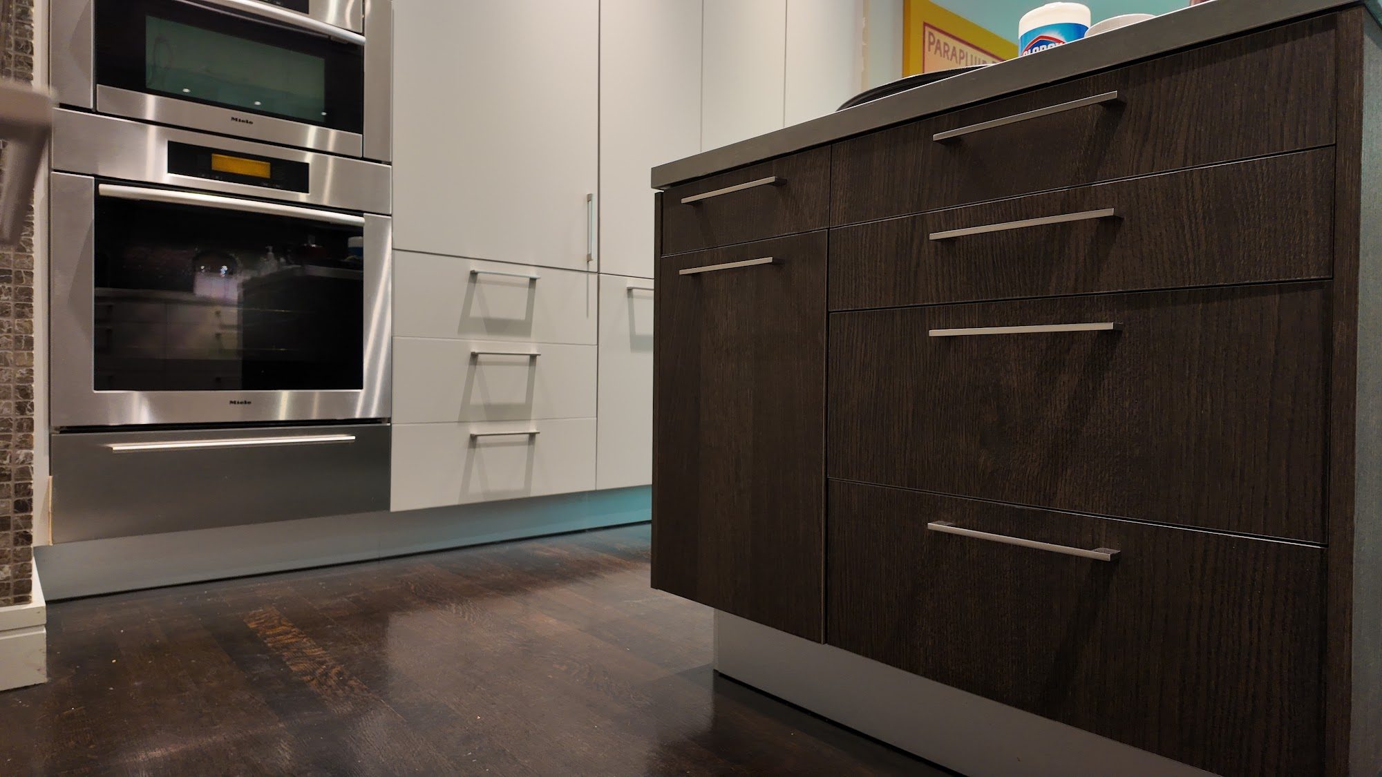 Water Street kitchen with walnut lower cabinets, glass-front uppers, and stone mosaic backsplash.